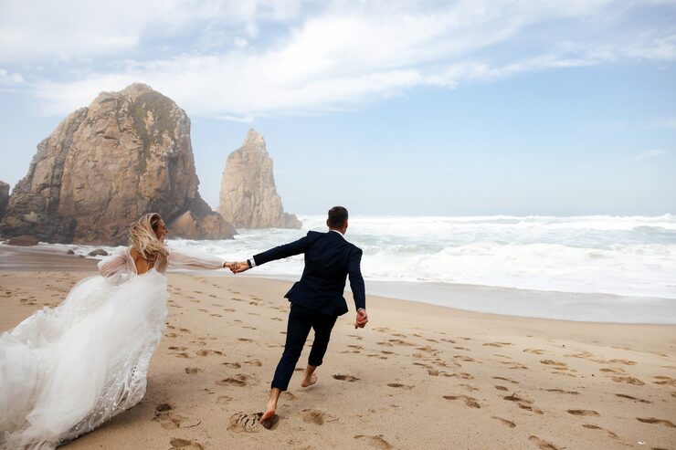 happy-newlyweds-holding-their-hands-are-running-across-beach-atlantic-ocean