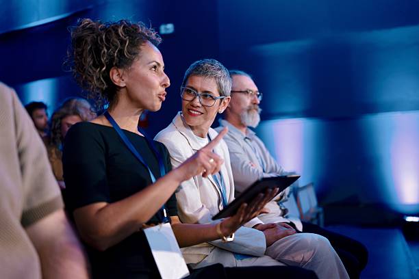 Diverse professionals attentively participate in a formal conference in a contemporary setting.