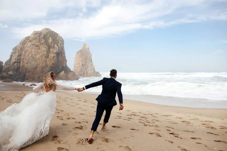 happy-newlyweds-holding-their-hands-are-running-across-beach-atlantic-ocean