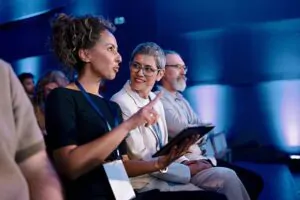 Diverse professionals attentively participate in a formal conference in a contemporary setting.