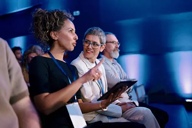 Diverse professionals attentively participate in a formal conference in a contemporary setting.